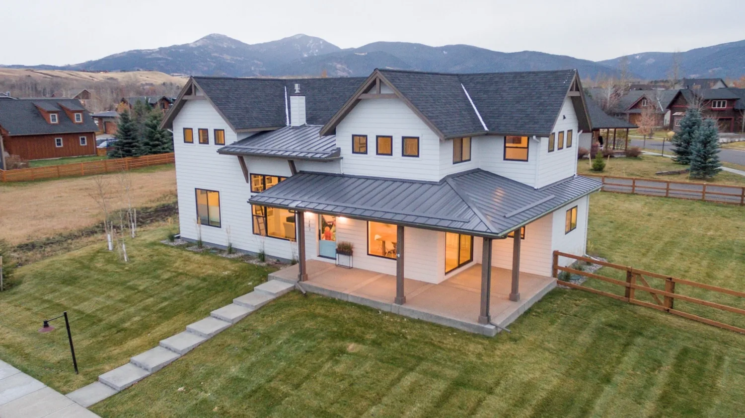 Modern farmhouse with a covered porch and the mountains behind it