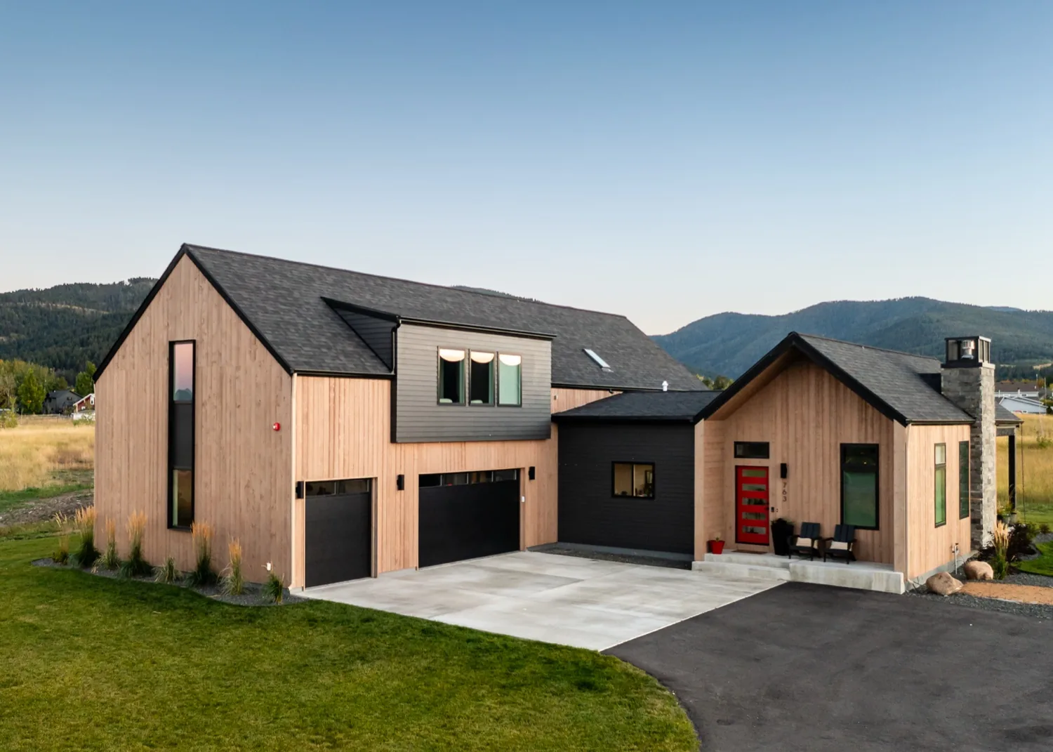 Modern home with vertical wood siding and black gables